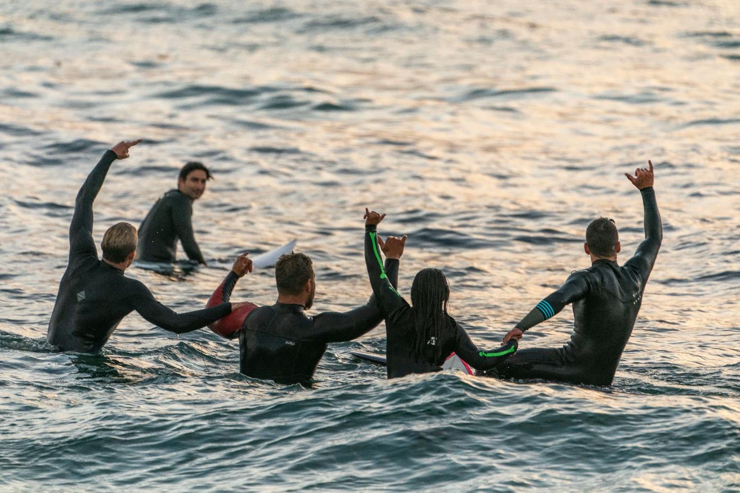 group of surfers holding hands supporting each other